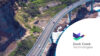 Bridge by the mountains and ocean, cars are driving. Duck Creek Technologies logo.