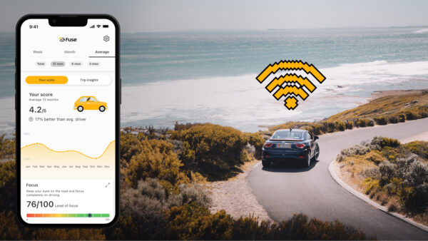 Car driving on a narrow road next to the ocean. Iphone showing Fuse Fleet app with your driver score.