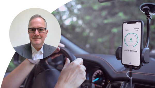 Person is driving with a phone showing 6 Risk level - Good driving!