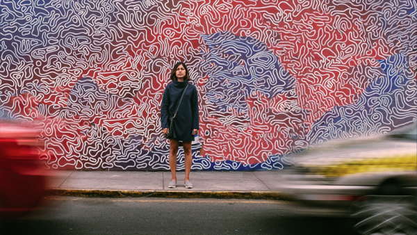 Woman standing on sidewalk looking to the other side of the street