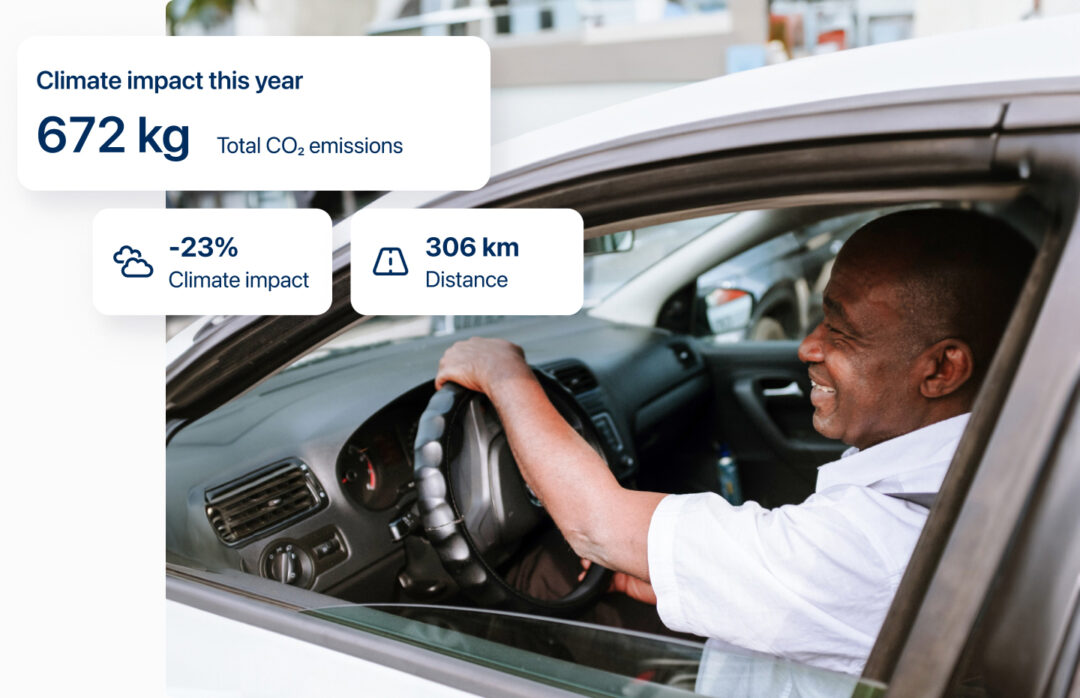 微笑みながら車を運転する男性の上に、CO2削減量(kg、%)と走行距離(km)を示すウィジェットが表示されている。
