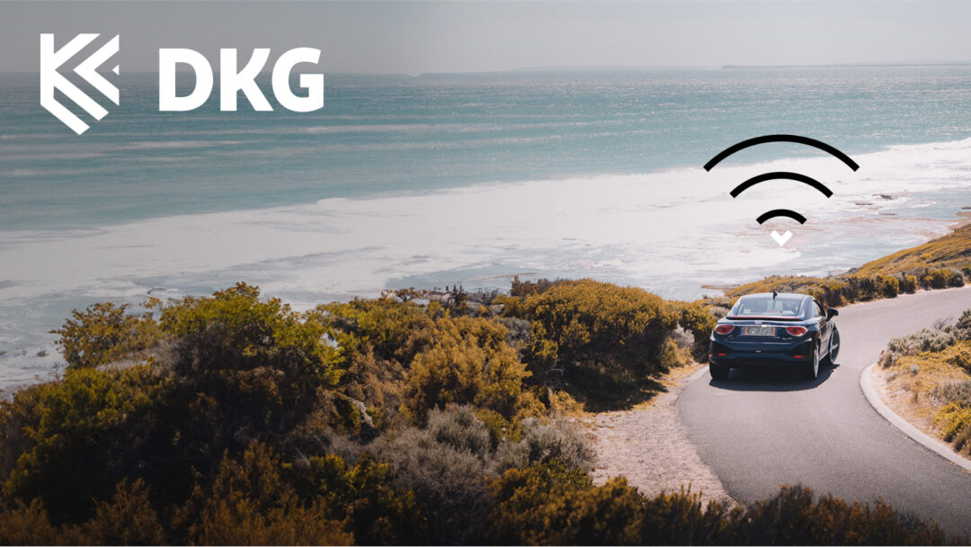 A black car driving by the beach with an icon above it showing it's connected, and the DKG logotype in the left upper corner