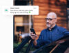 A middle-aged man standing beside a car, smiling as he looks at his phone. A notification overlay reads: 'Great news! Your driver risk has gone down. Keep up the safe driving!' with a green heart emoji.
