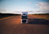 An EB Road Cargo branden truck from the front driving on a wide open road