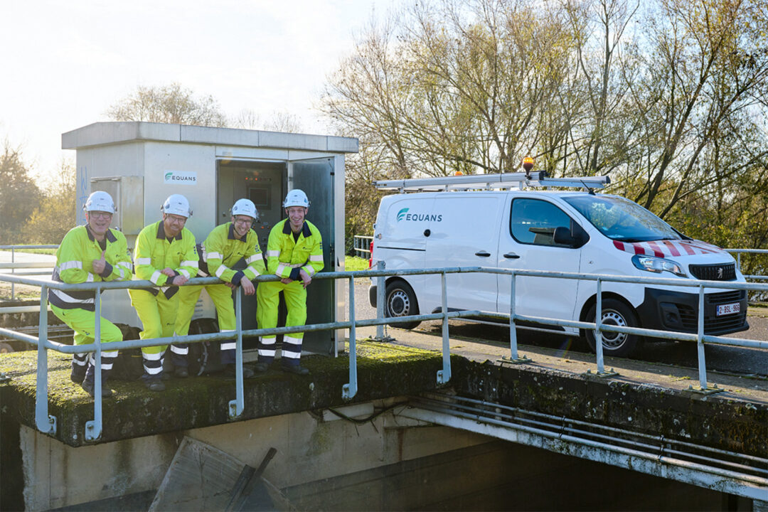 Equans field workers in high-visibility safety gear standing by a branded Equans service van near a utility facility, promoting eco-driving and fleet safety initiatives.