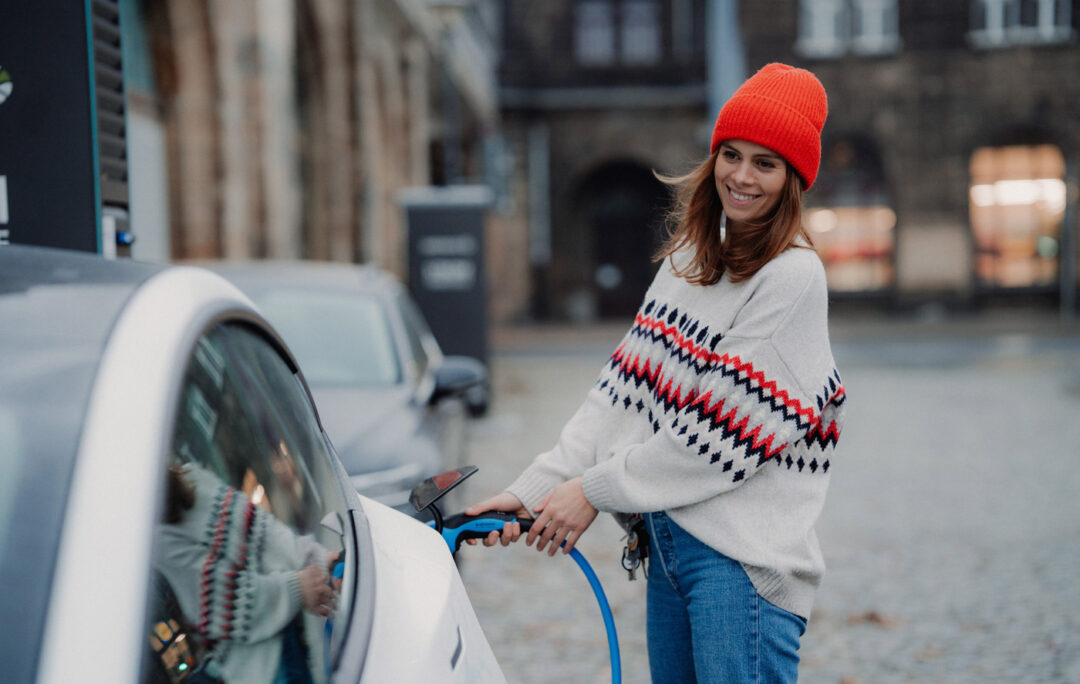 Woman standing and charging her electric car