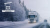雪と森に覆われた冬道を走る白い連結トラック。その横を乗用車が逆走している。左上にはEvald Karlsson Åkeriのロゴ。