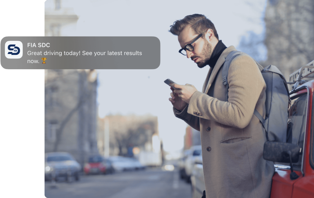 Man leans against a car and checking his phone. Notification from FIA SDC saying 