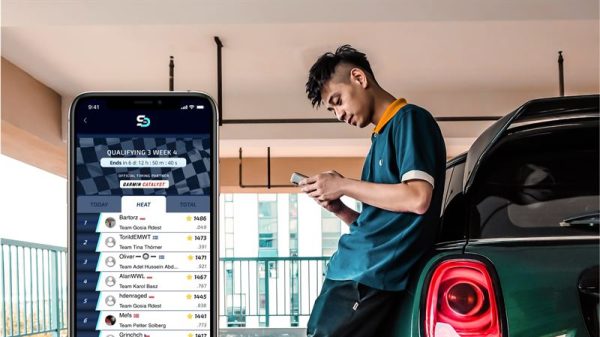 Man is looking at his phone, phone is showing FIA smart driving challenge app