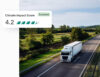 White semi-truck driving on a scenic rural highway surrounded by green fields and trees. An overlay shows a 'Climate Impact Score' of 4 out of 5 leaves, labeled 'Excellent', indicating strong emissions performance.