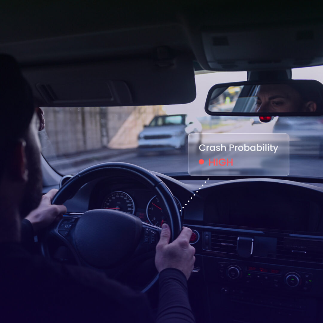 Interior view from behind a driver steering a car, looking through the windshield at oncoming traffic. A transparent digital overlay connects a dotted line from the dashboard to a floating panel that reads, 