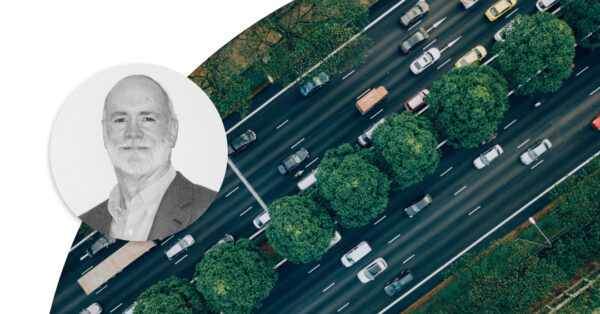 Cars driving on an avenue with green threes around it. Profile image of Jim Noble.