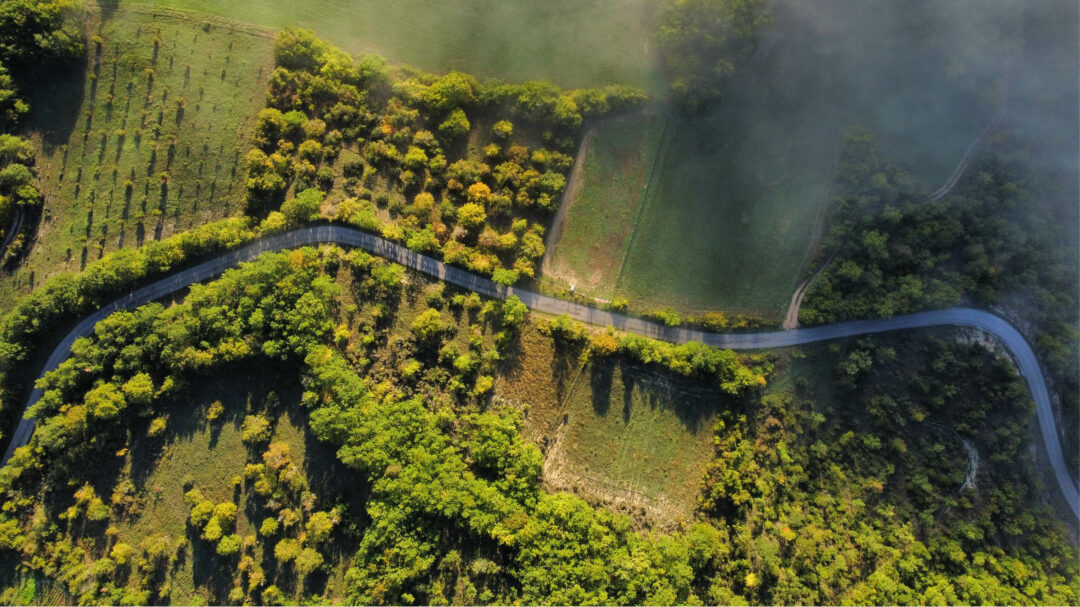 Fileds and a winding road from above with a clouds on its way in