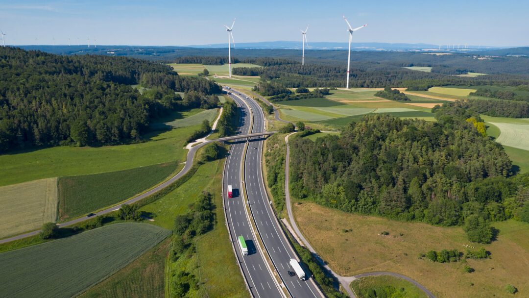 Road going through the country side with blue sky and windmills.