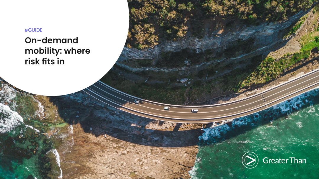 Road that winds along a mountain and the water's edge with three white cars driving in the same direction.