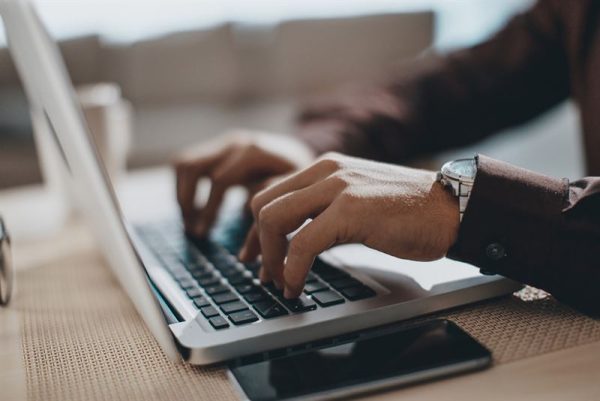 Hands typing on a laptop