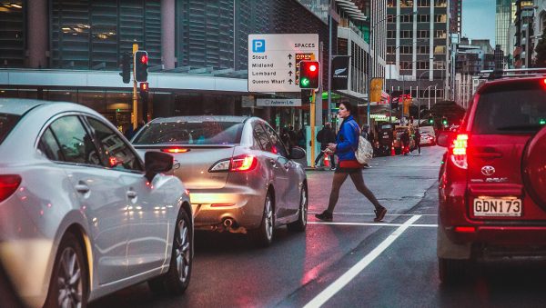 Cars waiting at red light and woman crossing the street