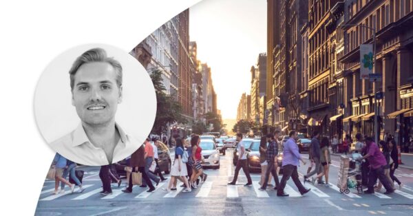 People crossing a street with sunlight coming in from behind buildings. Profile image of Johan Forseke.