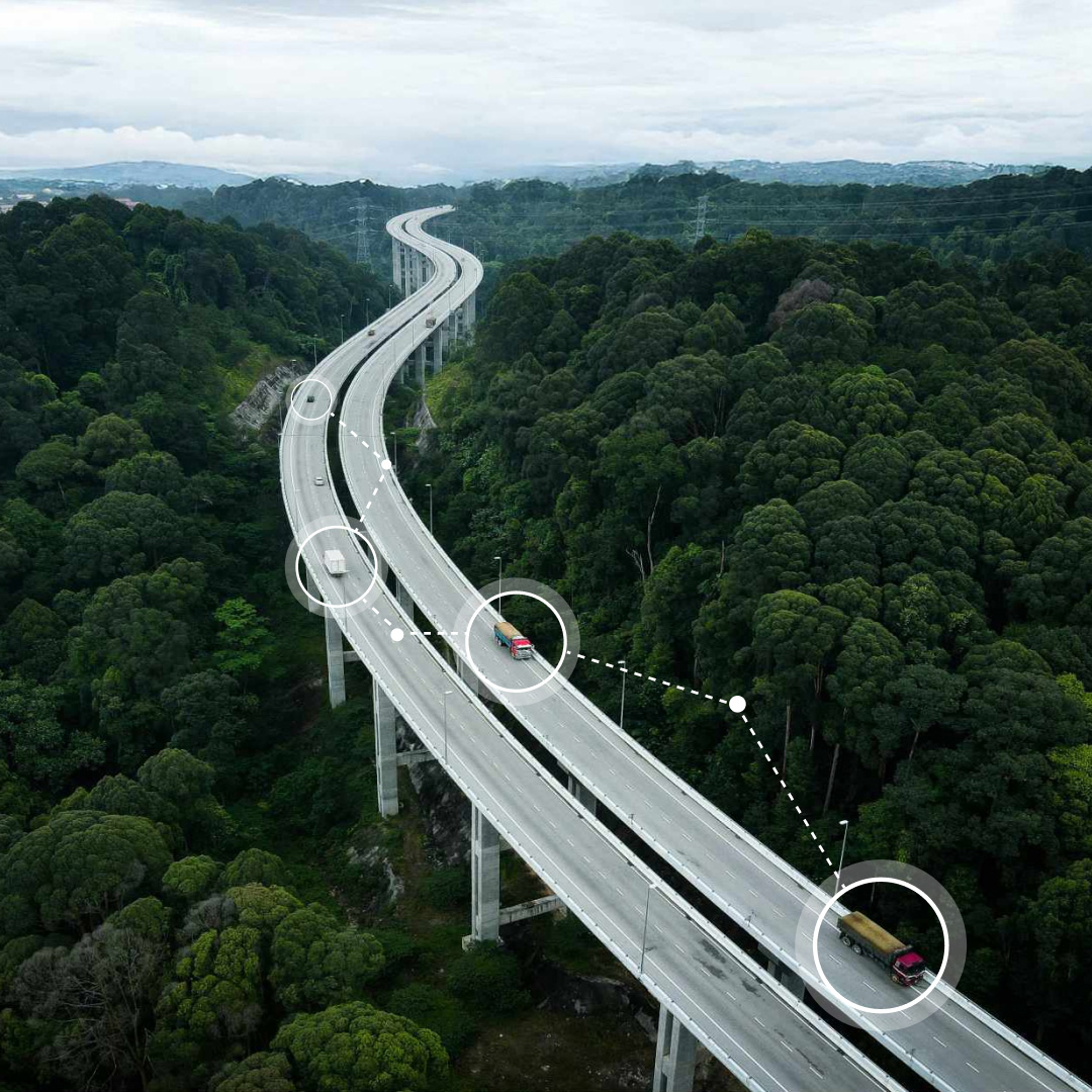 Aerial view of a highway bridge cutting through a lush forest, with AI-powered telematics technology highlighting vehicle positions to visualize traffic and driving behavior insights.