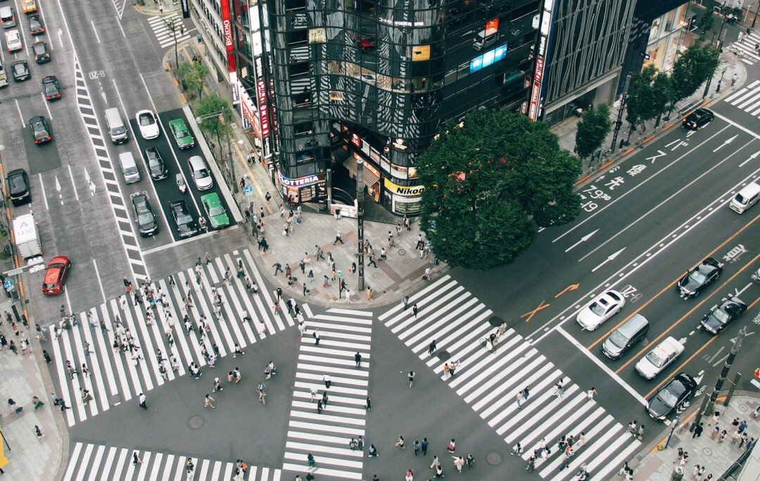 Large crossroad in Tokyo where people crossing the street while the cars are waiting